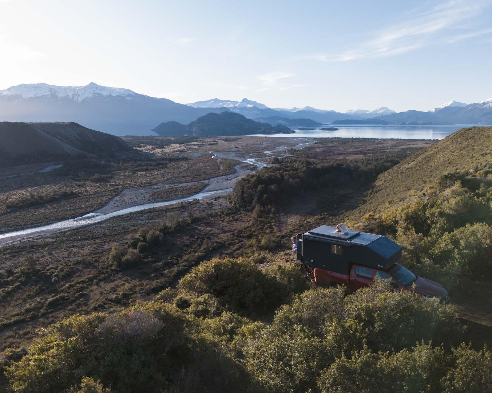 A Yeti camper parked on a ridge in Aysén, looking over a braided river, a lake and the Andes at golden hour