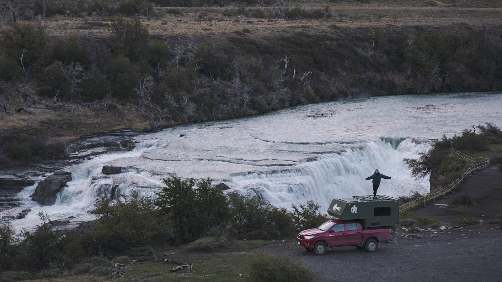 Nomad Camper at Salto Grande, Torres del Paine, with a traveller standing on the roof